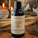 Bottle of Raw Root Hydrating Shampoo on a wooden surface with candles and lavender in the background