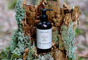 Bottle of Raw Root Aloe Manuka Gel on a wooden surface with greenery