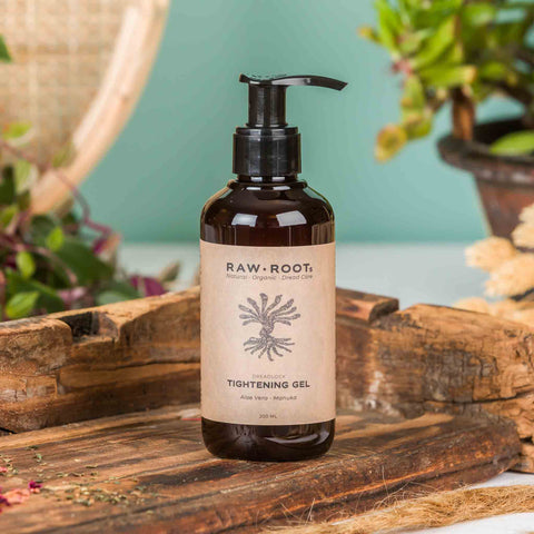 Bottle of Raw Root Tightening Gel on a wooden surface with plants in the background