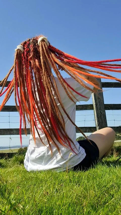 Long red, orange and blonde dreadlock extensions outdoors