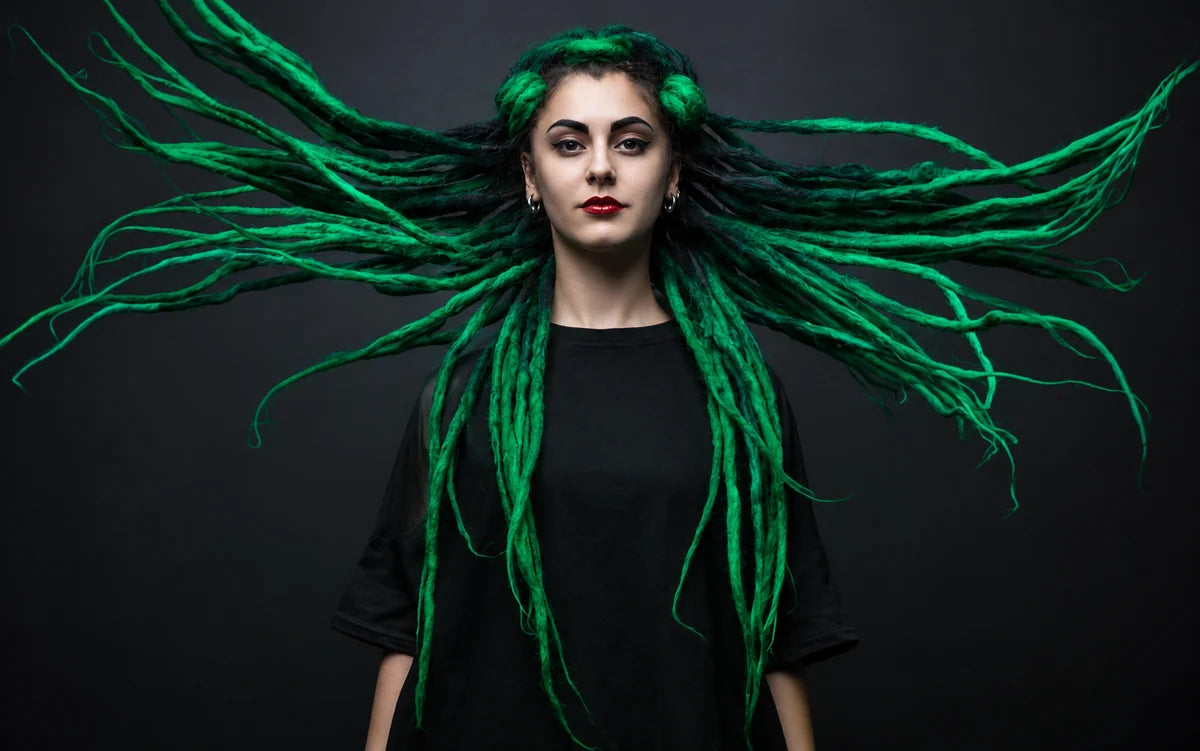 Green dreadlocks fanned out against a dark background
